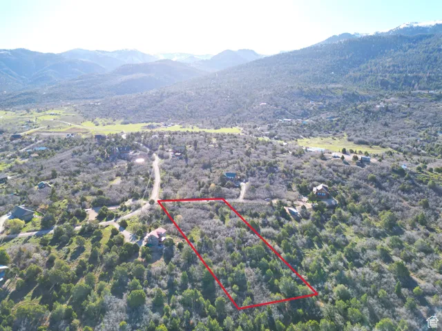 Aerial view of property and surrounding area featuring mountains and property parcel outlined