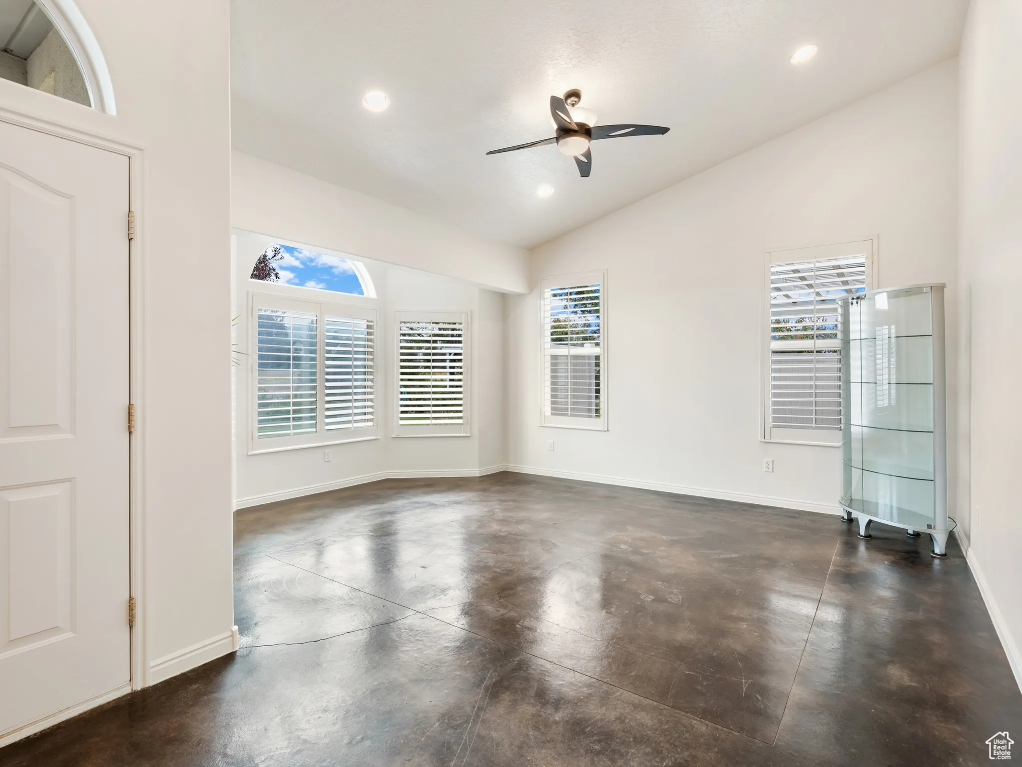 Unfurnished room featuring finished concrete flooring, recessed lighting, a ceiling fan, and high vaulted ceiling