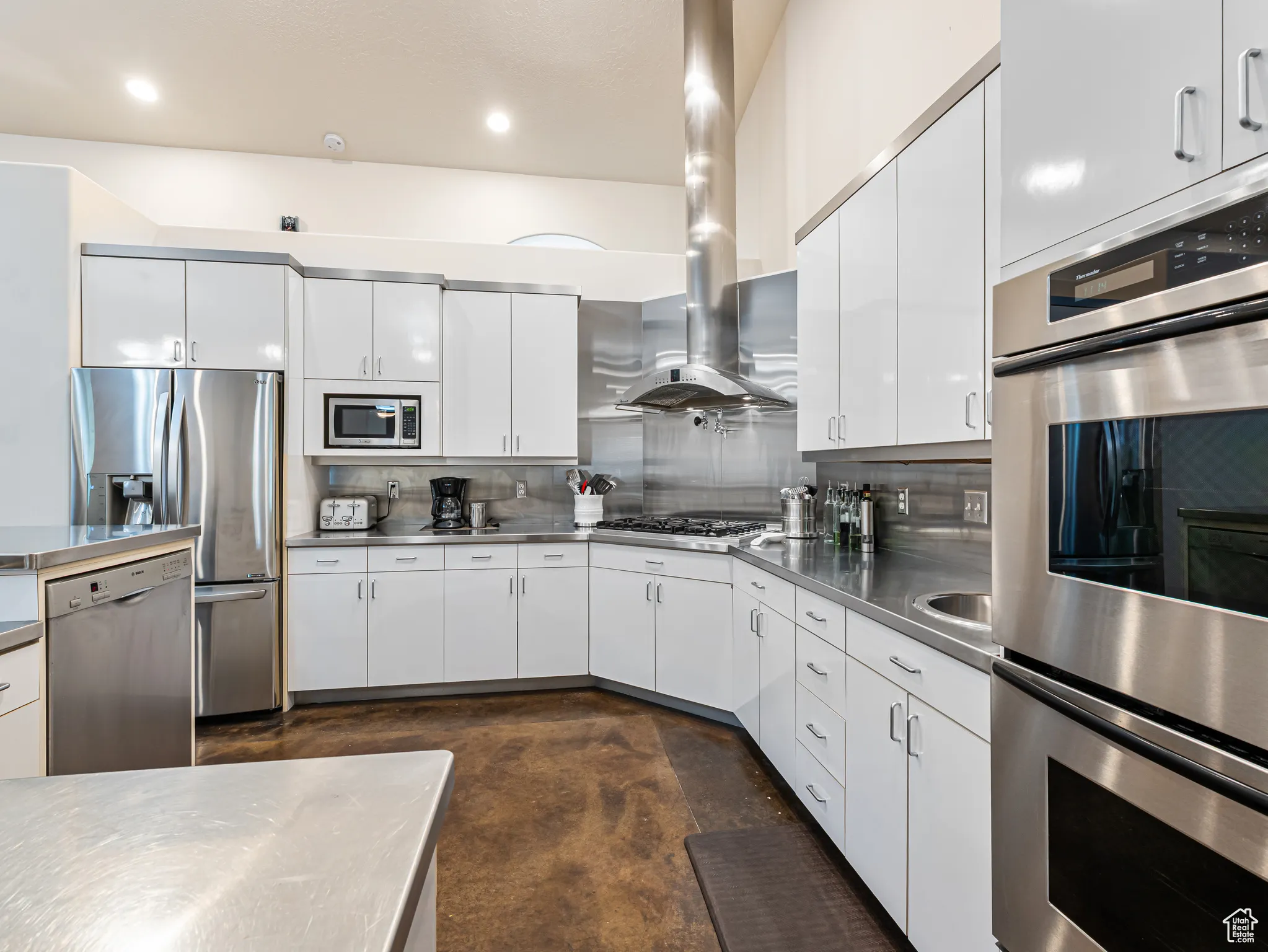Kitchen featuring stainless steel counters, appliances with stainless steel finishes, plenty of cabinet storage, backsplash, Gas Cook top and exhaust hood, Extra Prep sink next to double Ovens