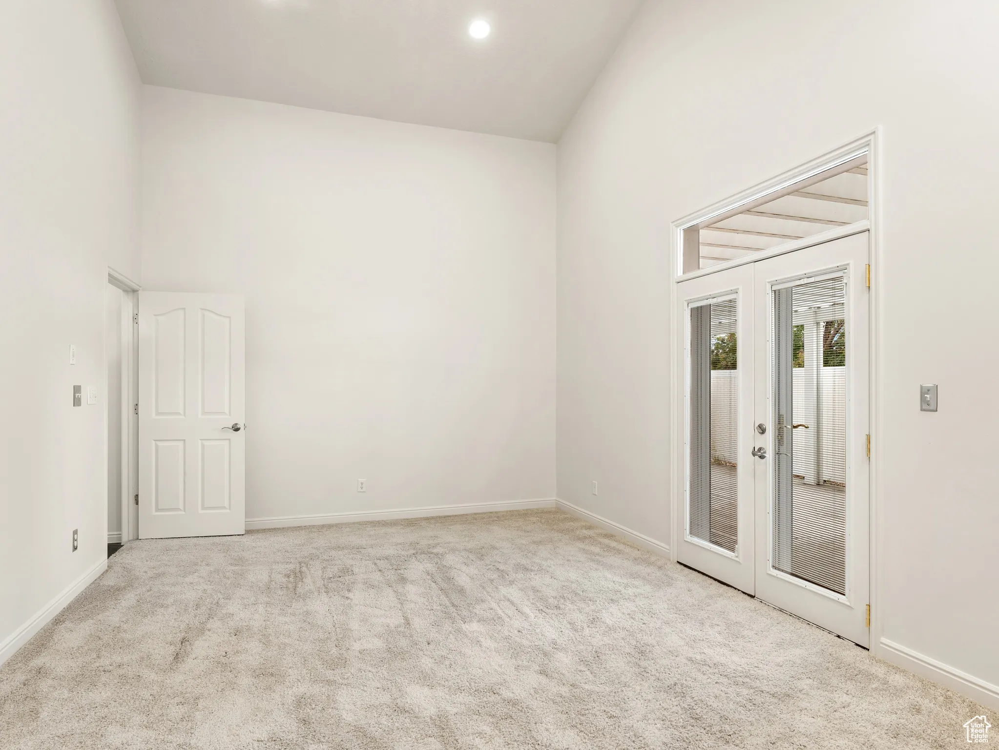 Unfurnished room featuring high vaulted ceiling, french doors, and light colored carpet