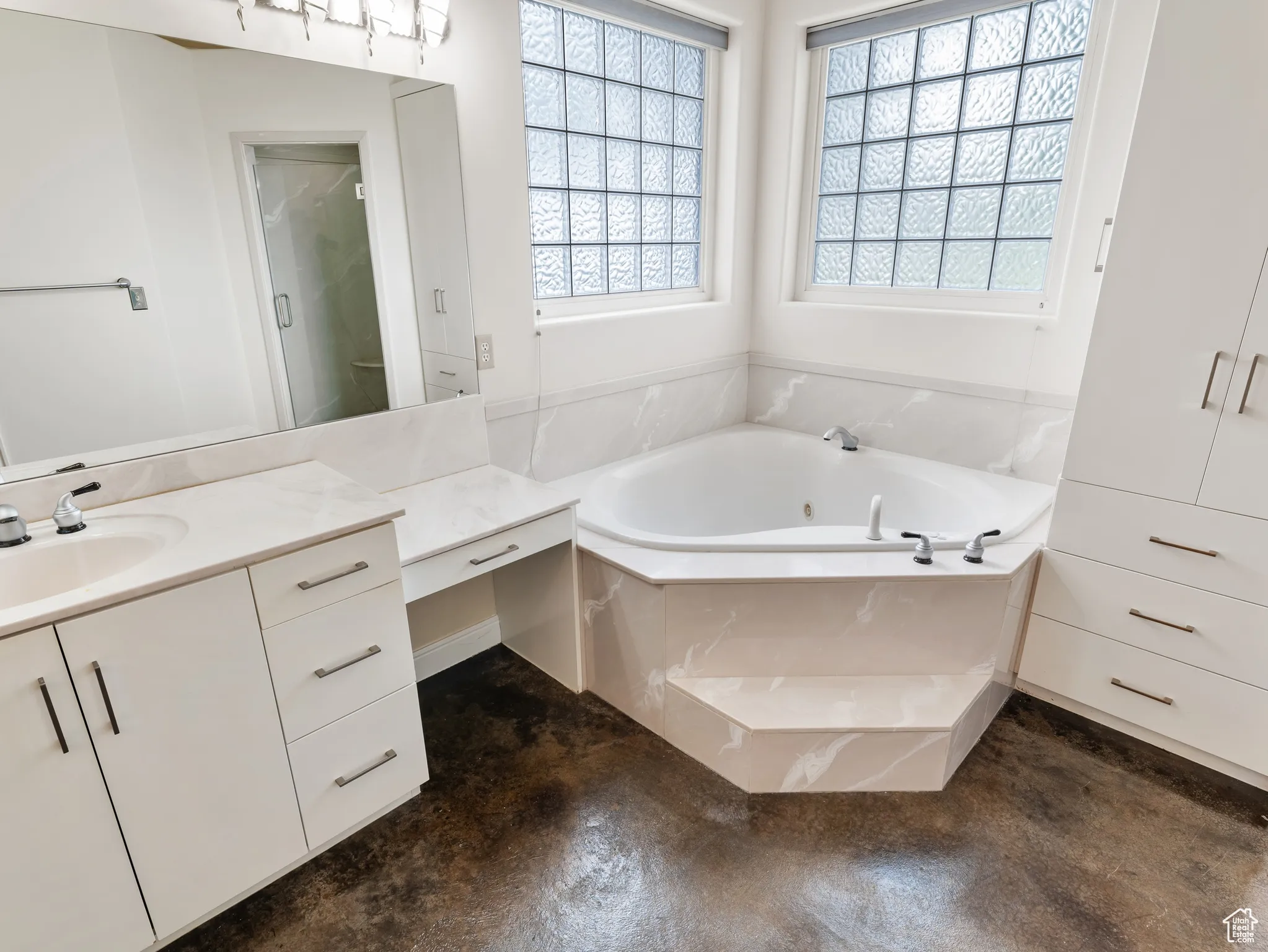 Bathroom with vanity, a tub with jets, finished concrete flooring, and an enclosed shower