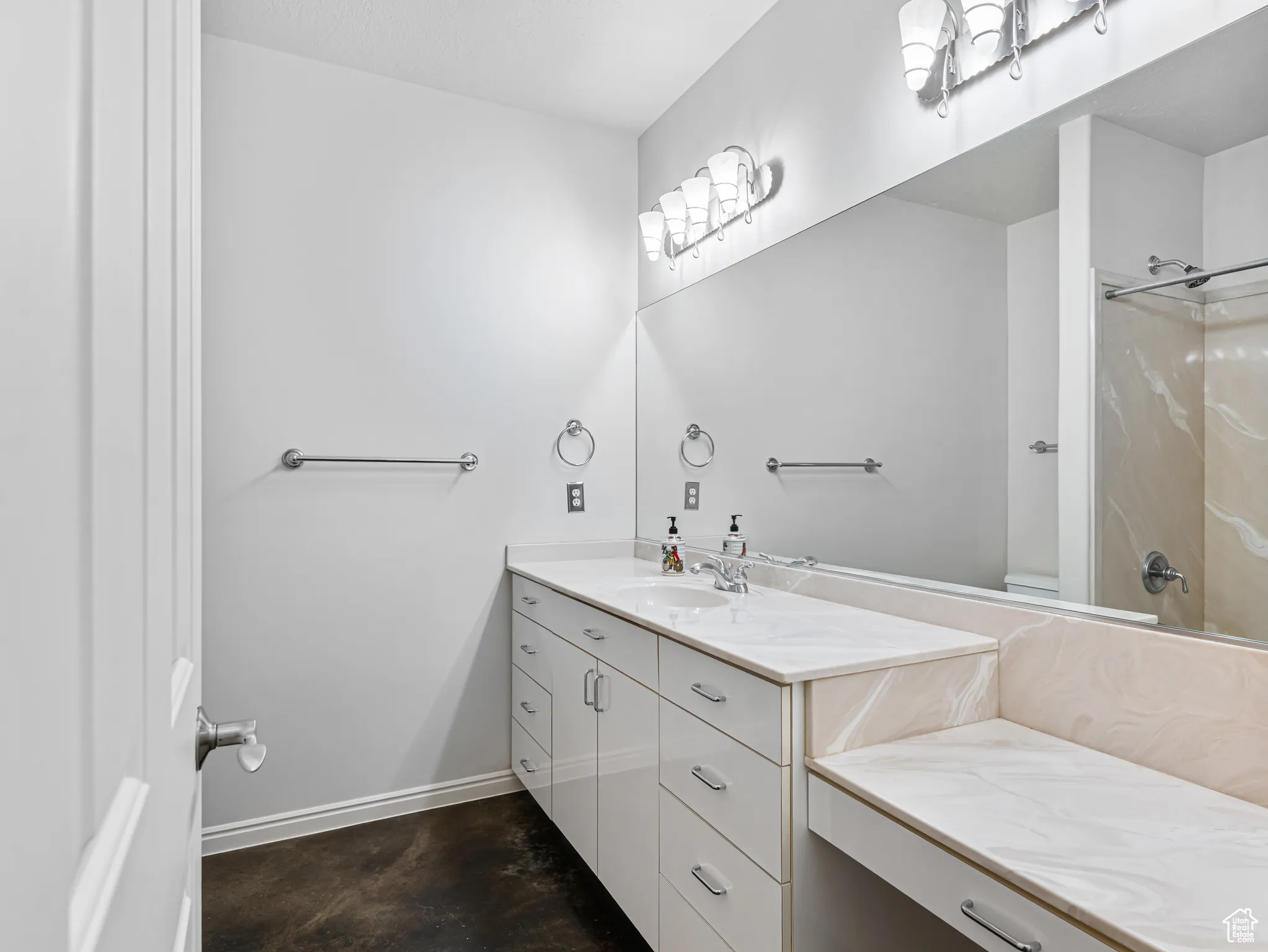 Bathroom featuring vanity,  jetted tub / shower combination, and concrete floors