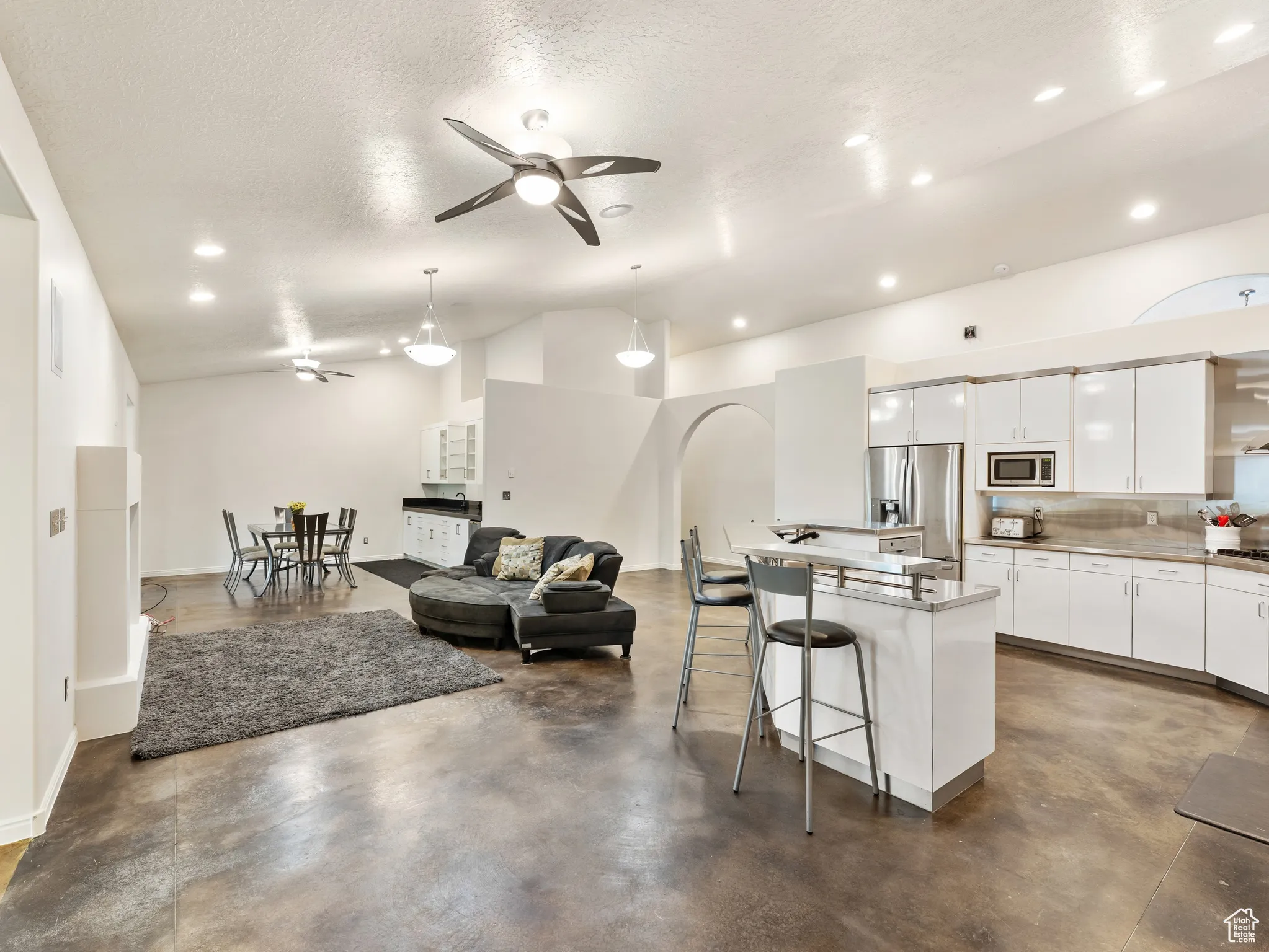 Living area with ceiling fan, recessed lighting, finished concrete flooring, a textured ceiling, and lofted ceiling