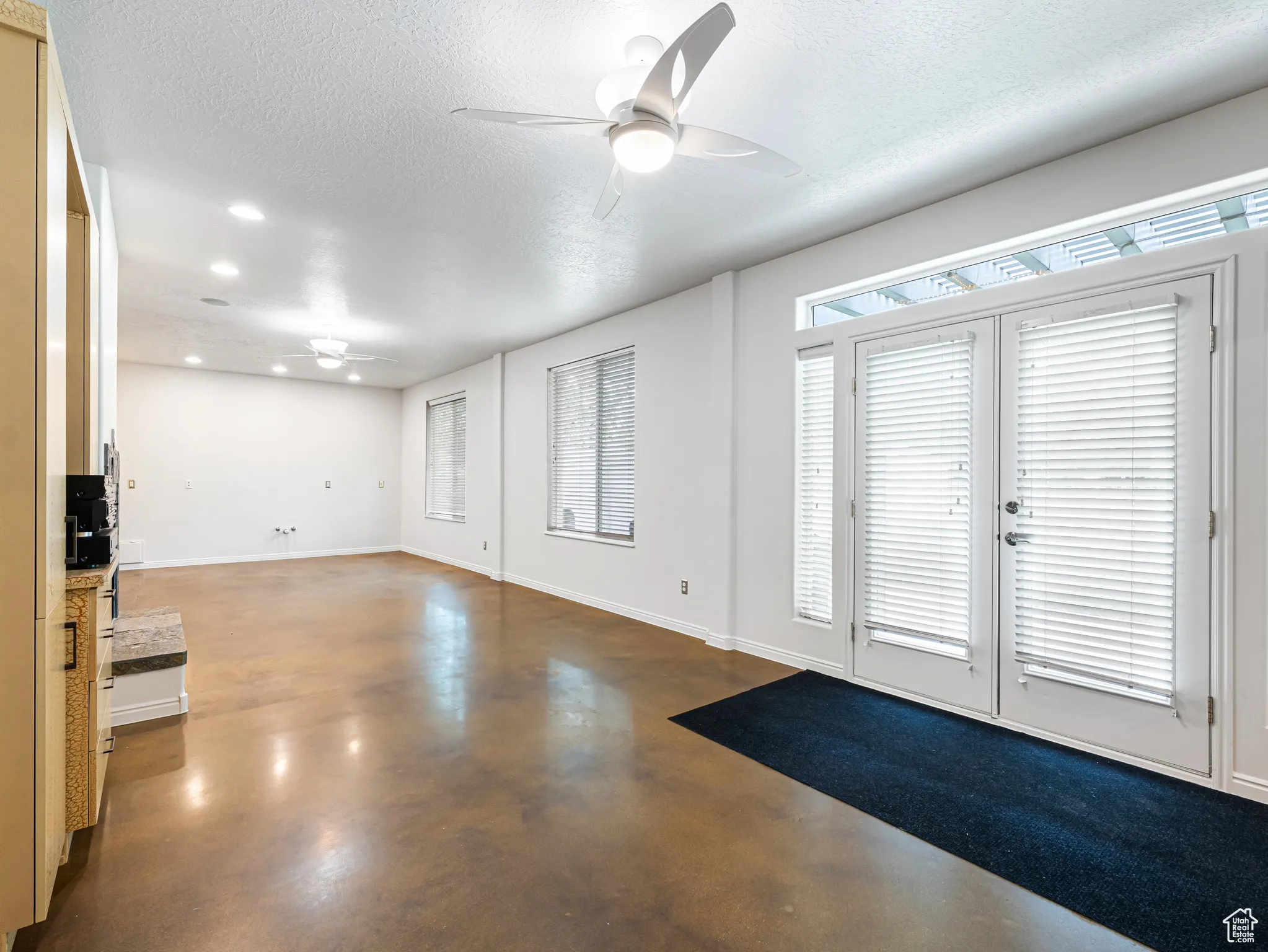 Entrance foyer with a ceiling fan, finished concrete floors, a textured ceiling, french doors, and recessed lighting