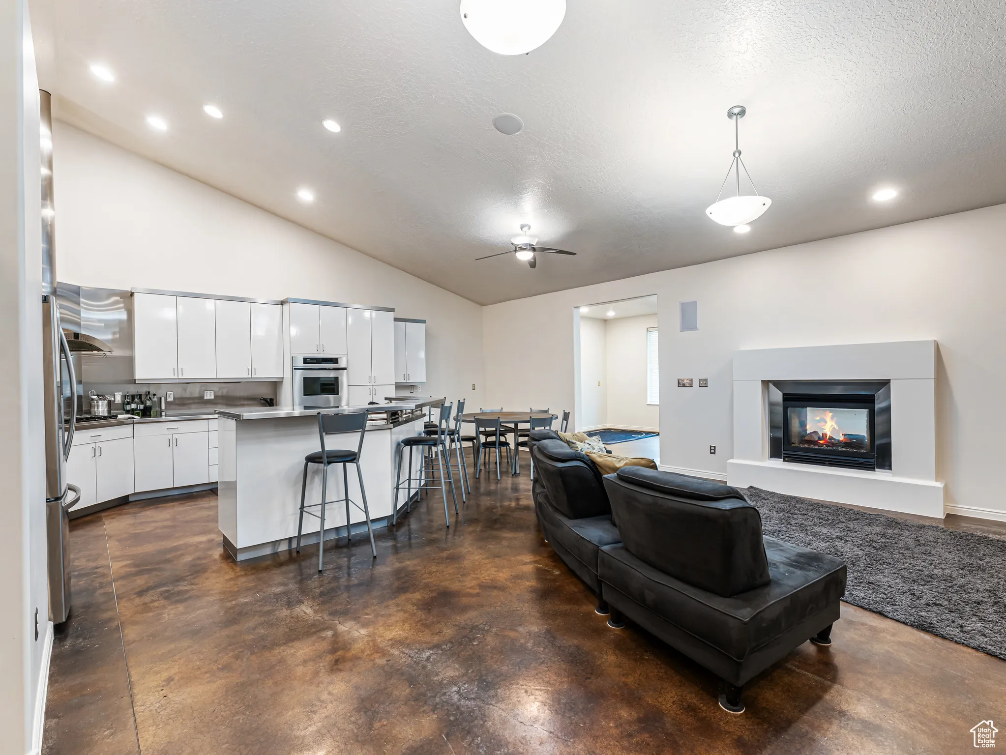 Great Room with 2 ceiling fans, recessed lighting, a multi sided fireplace, lofted ceiling, and finished concrete flooring