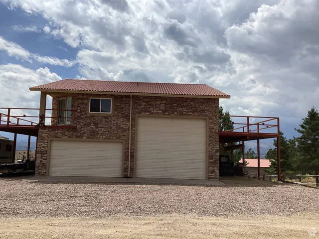 View of side of home featuring stone siding, driveway, and a deck