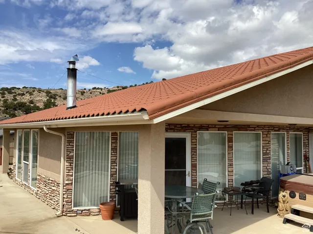 Rear view of property with stone siding, stucco siding, and a patio