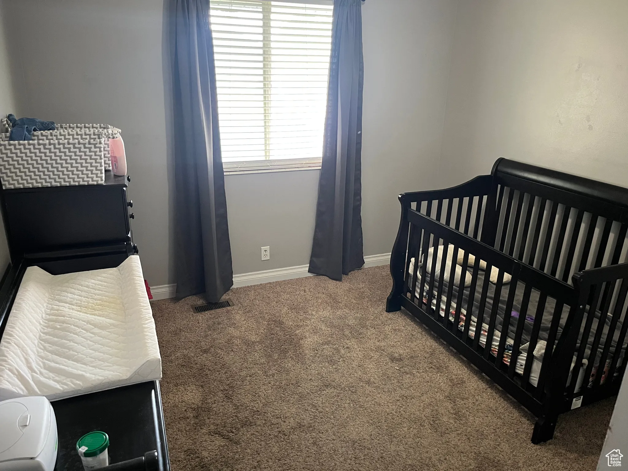 Carpeted bedroom with a crib and baseboards