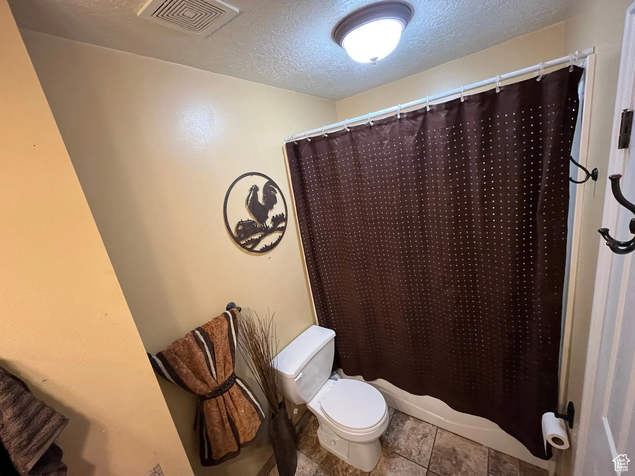 Full bathroom featuring a textured ceiling and shower / bathtub combination with curtain