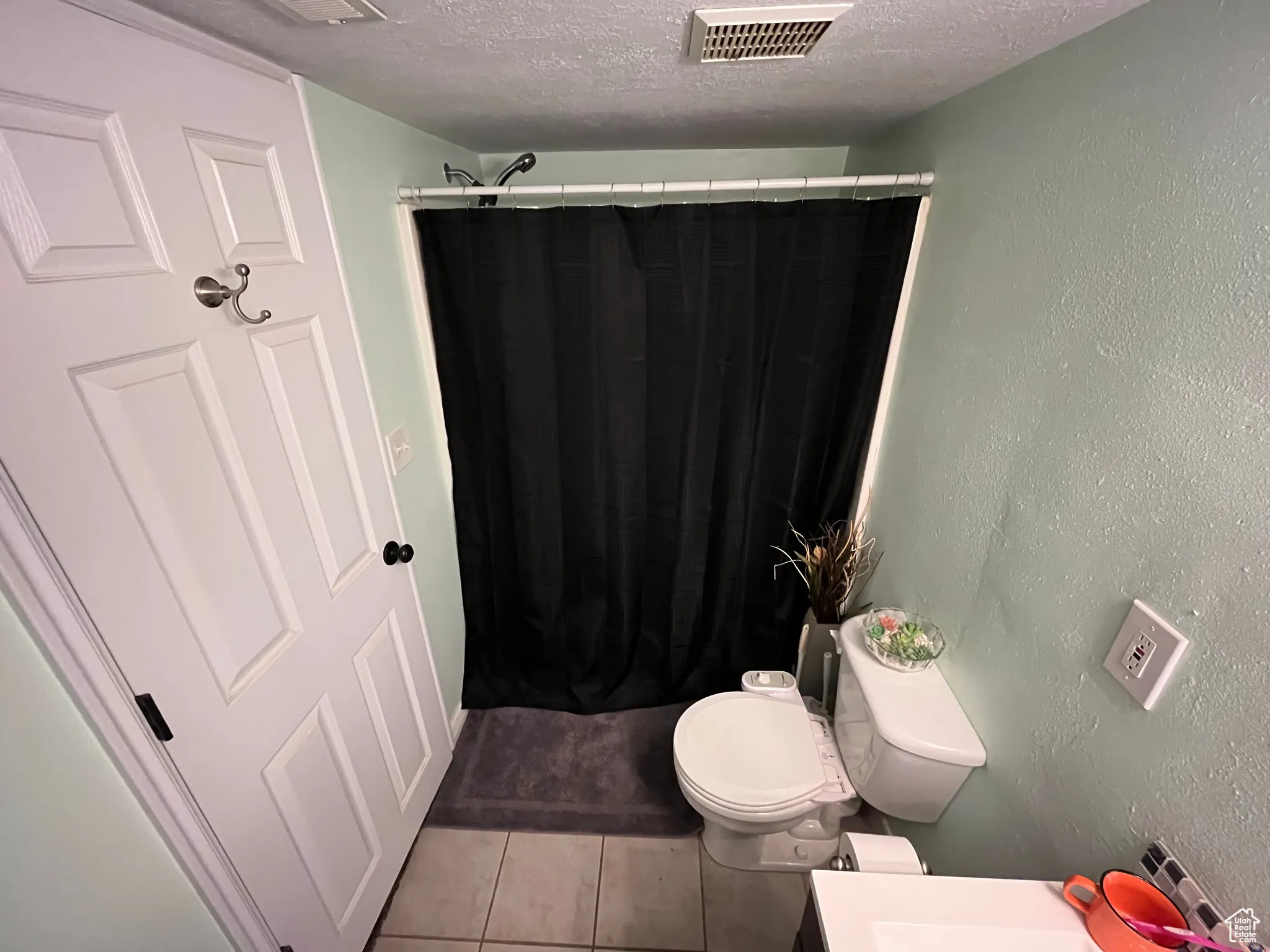 Bathroom with tile patterned flooring, a textured ceiling, a shower with shower curtain, a textured wall, and vanity