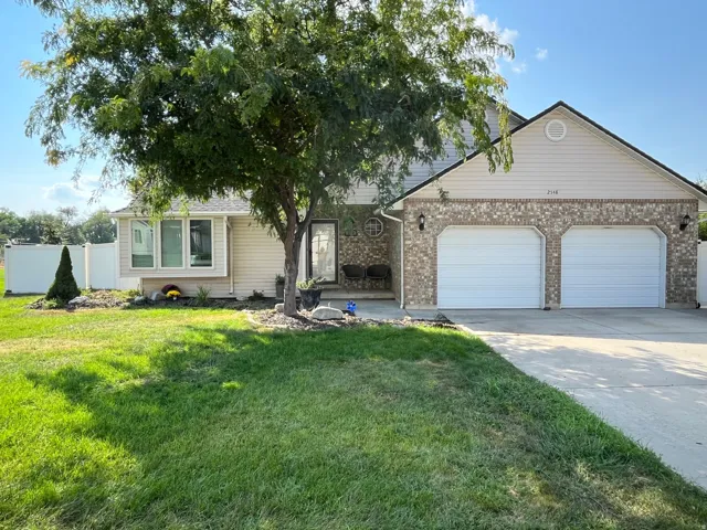 View of front of home with concrete driveway, an attached garage, brick siding, and a patio area