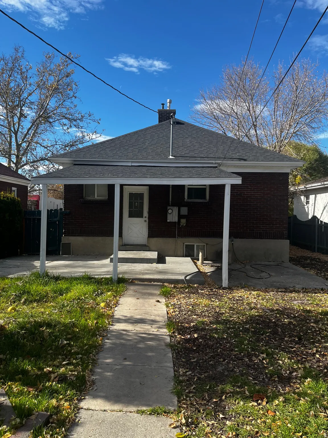 Rear view of property featuring covered porch, a shingled roof, and brick siding