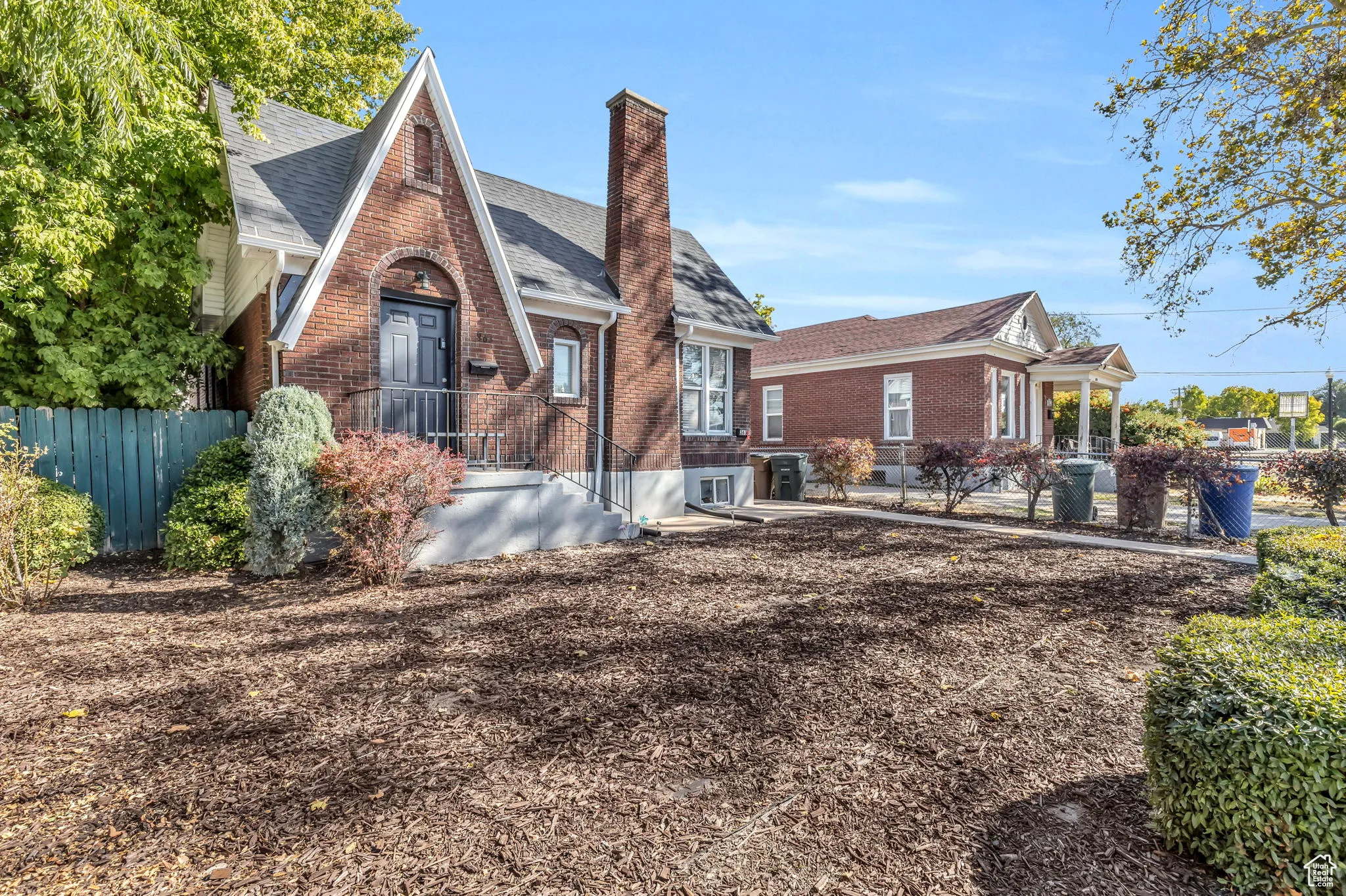 View of front of property with brick siding, a chimney, and a shingled roof