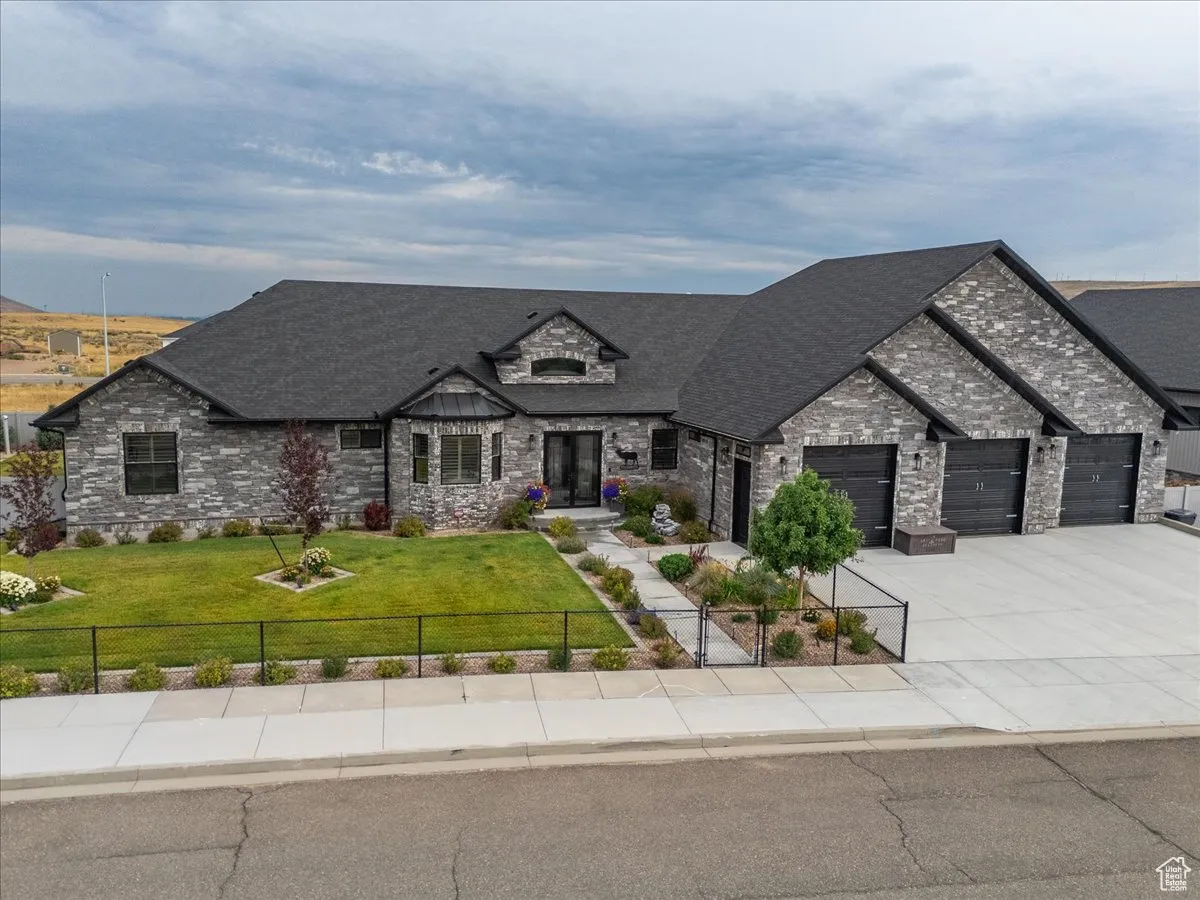 French country style house with concrete driveway, stone siding, a garage, and roof with shingles