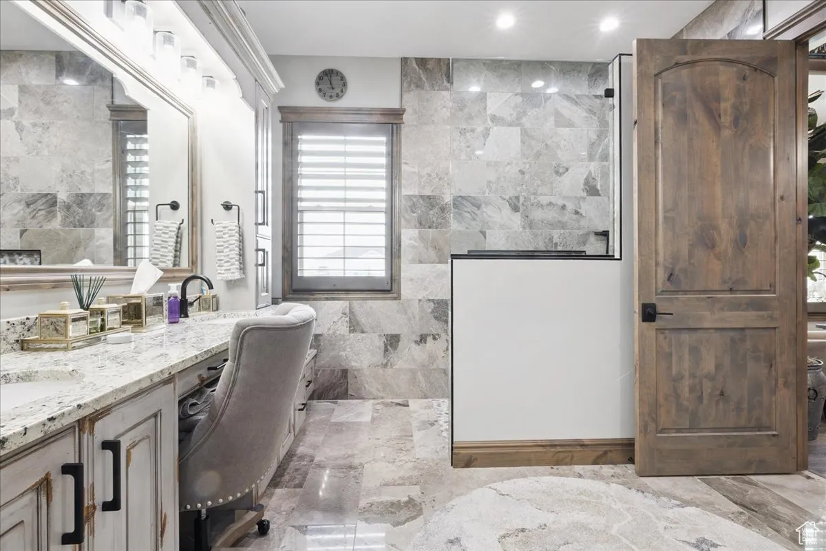Full bathroom with tile walls, walk in shower, and vanity