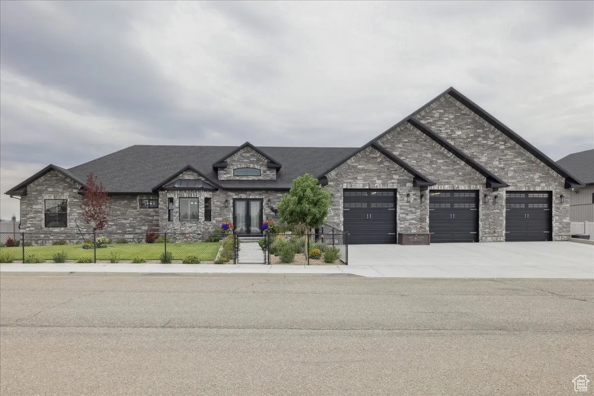 View of front facade featuring stone siding, concrete driveway, and a garage
