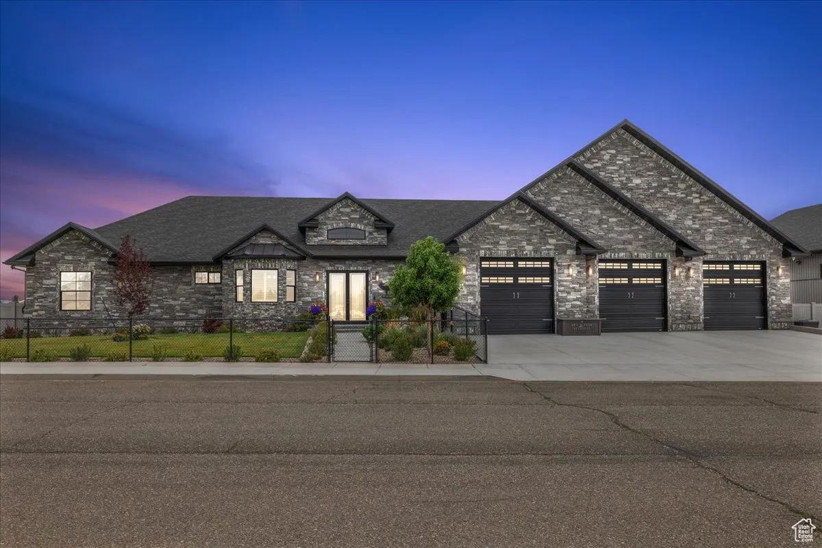 French provincial home featuring stone siding, concrete driveway, an attached garage, and roof with shingles