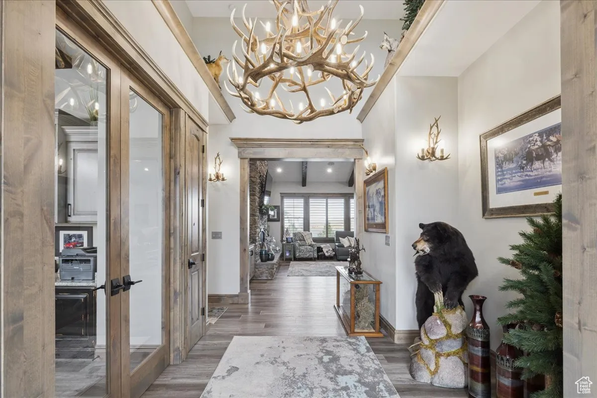 Hallway featuring light wood-style floors, a chandelier, and beamed ceiling