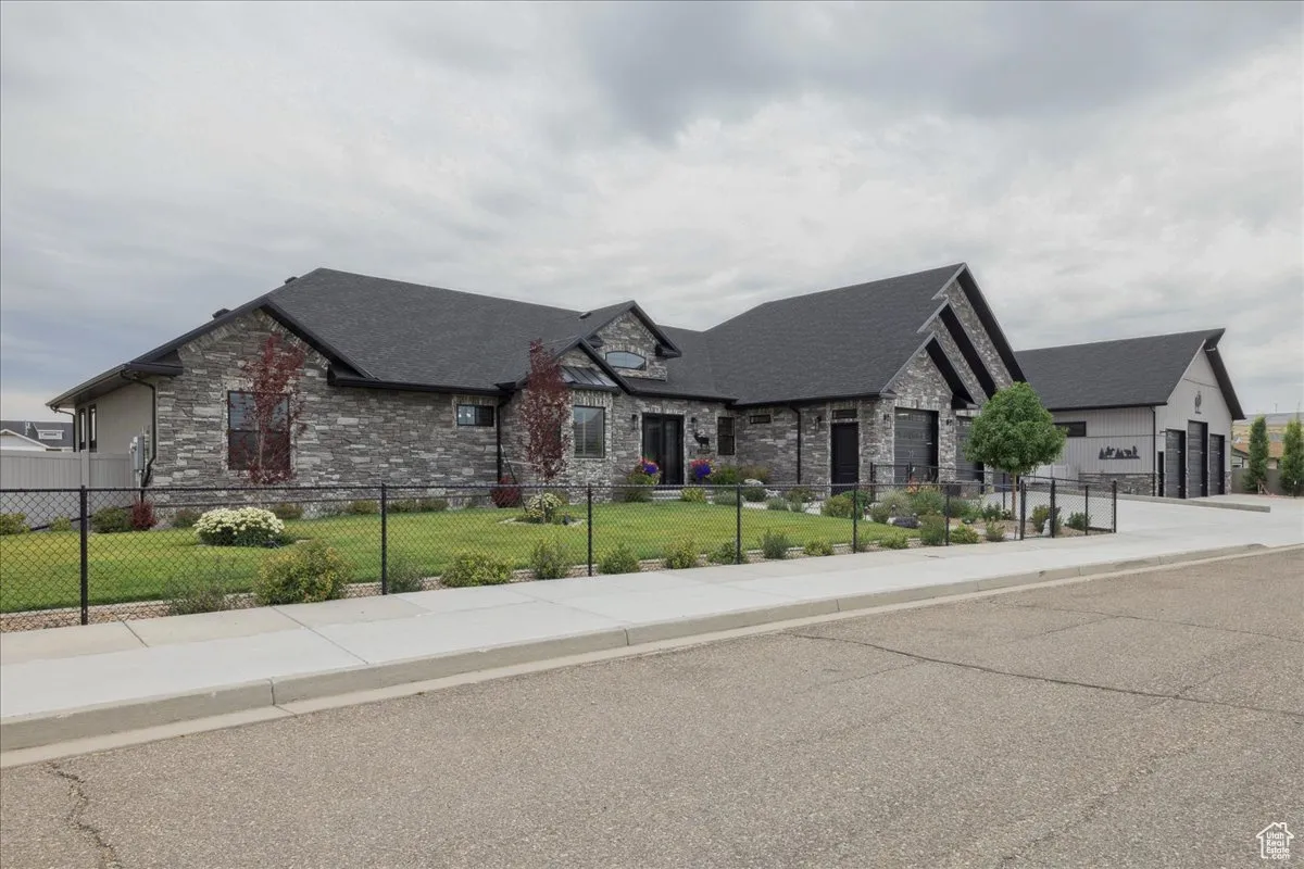 View of front of property with stone siding and roof with shingles