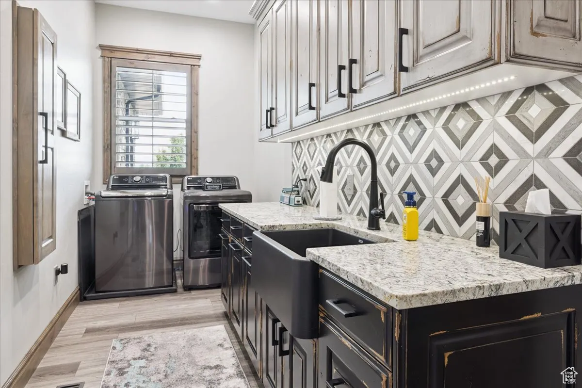 Laundry room featuring light wood-type flooring, cabinet space, and separate washer and dryer