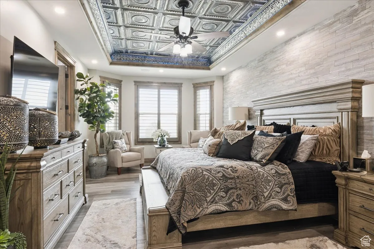 Bedroom featuring an ornate ceiling, wood finished floors, a ceiling fan, a raised ceiling, and recessed lighting
