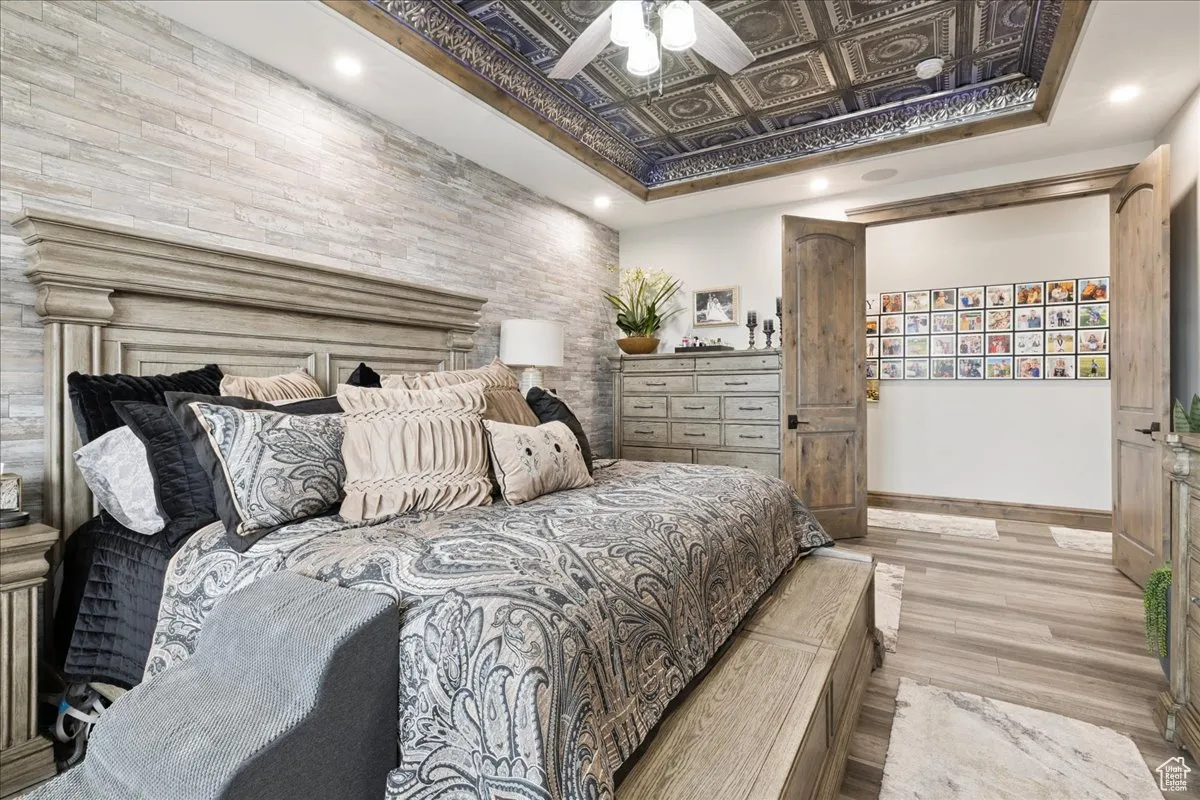 Bedroom featuring an ornate ceiling, light wood finished floors, recessed lighting, a raised ceiling, and a ceiling fan