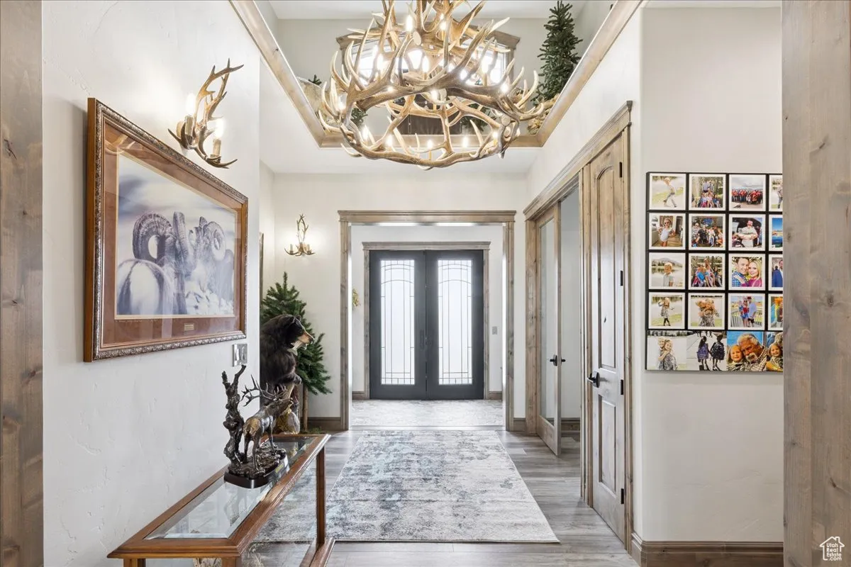 Entrance foyer with light wood-type flooring, french doors, and a chandelier