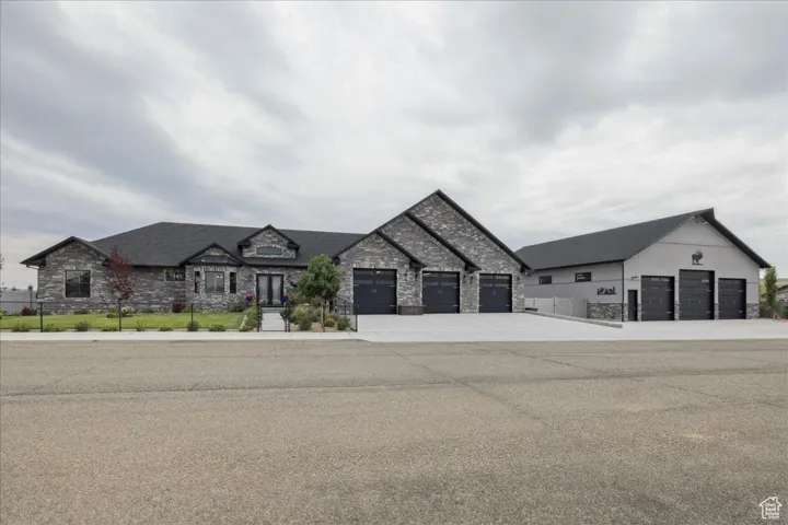 View of front facade featuring stone siding, driveway, and an attached garage