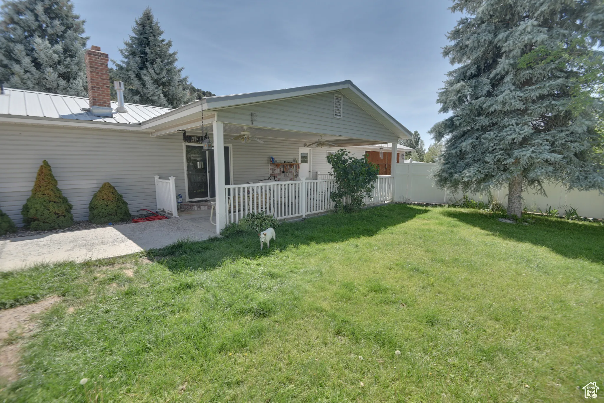 Rear view of property featuring a ceiling fan, a metal roof, a patio, a chimney, and a standing seam roof