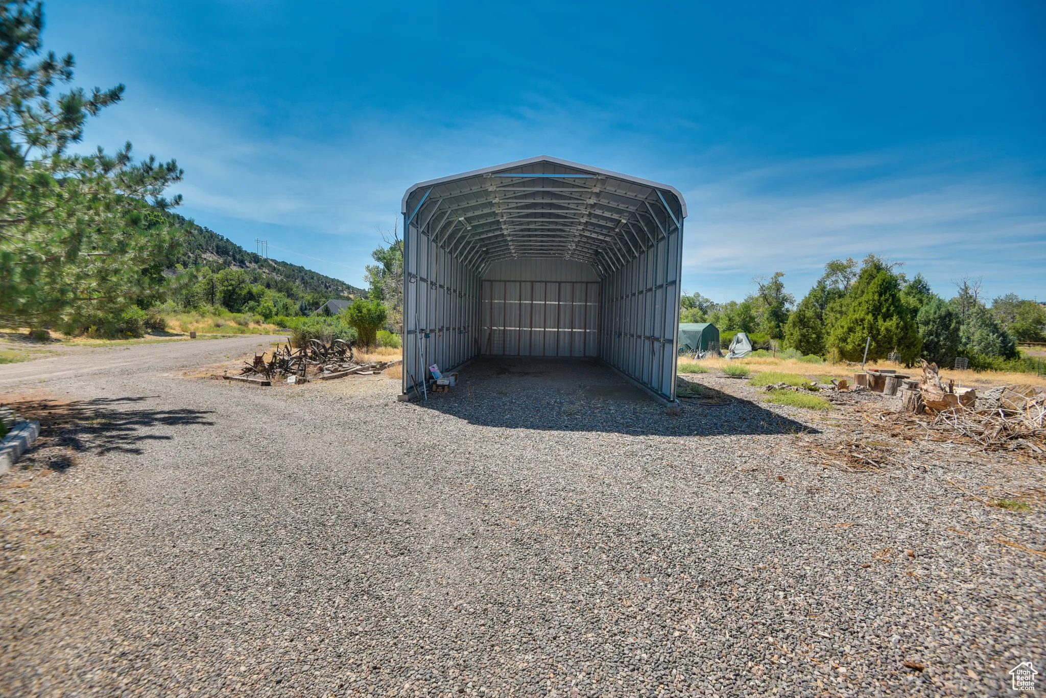 View of outbuilding with a detached carport and gravel driveway