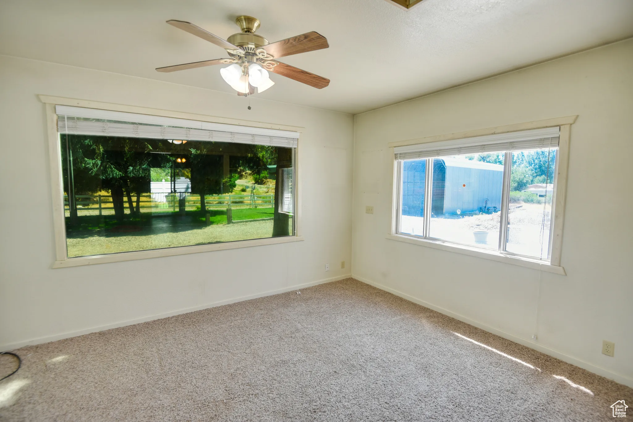 Carpeted spare room with baseboards and ceiling fan