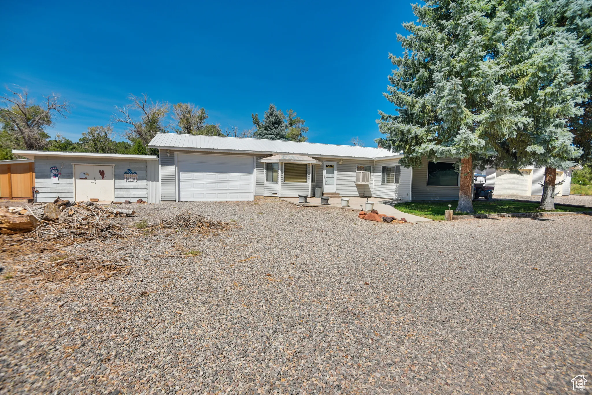 Ranch-style house with driveway, an attached garage, and a metal roof