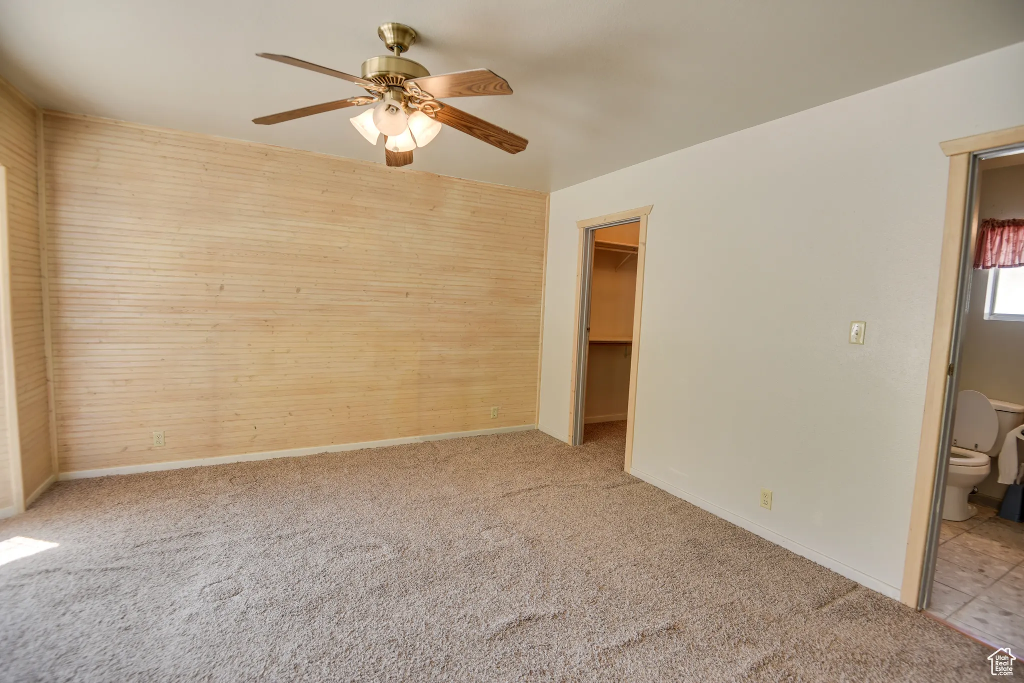 Unfurnished bedroom featuring carpet flooring, a spacious closet, a ceiling fan, and connected bathroom