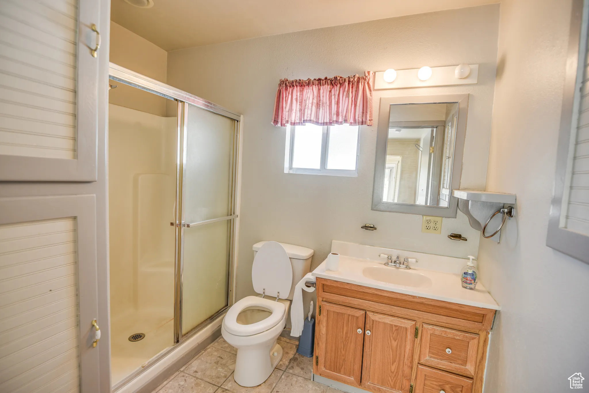 Full bath featuring a shower stall, vanity, and light tile patterned floors