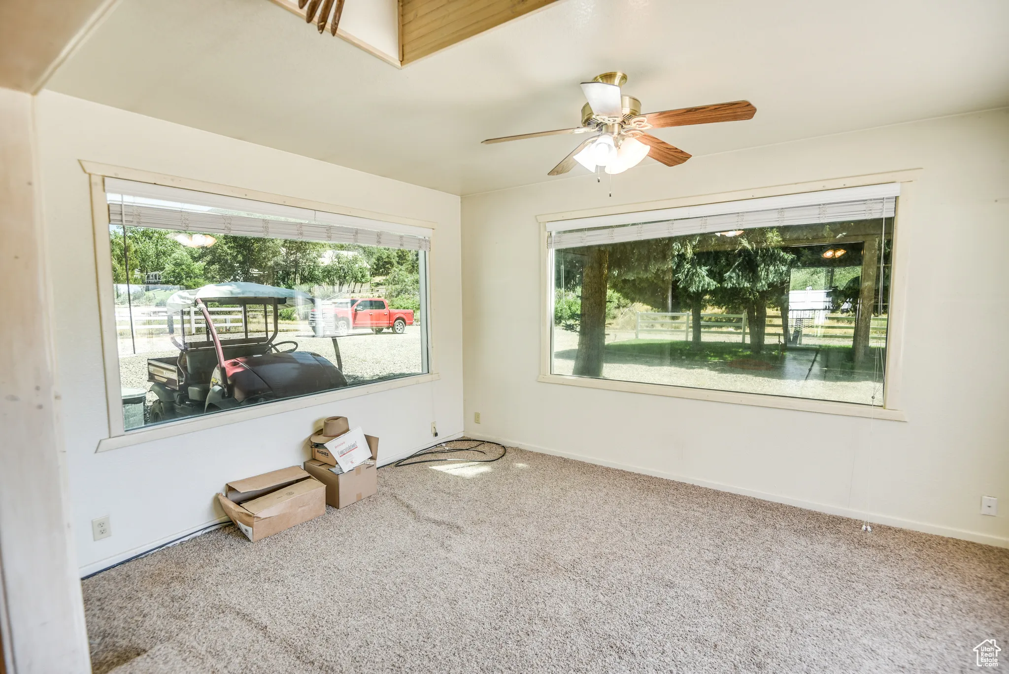 Carpeted empty room featuring baseboards and a ceiling fan