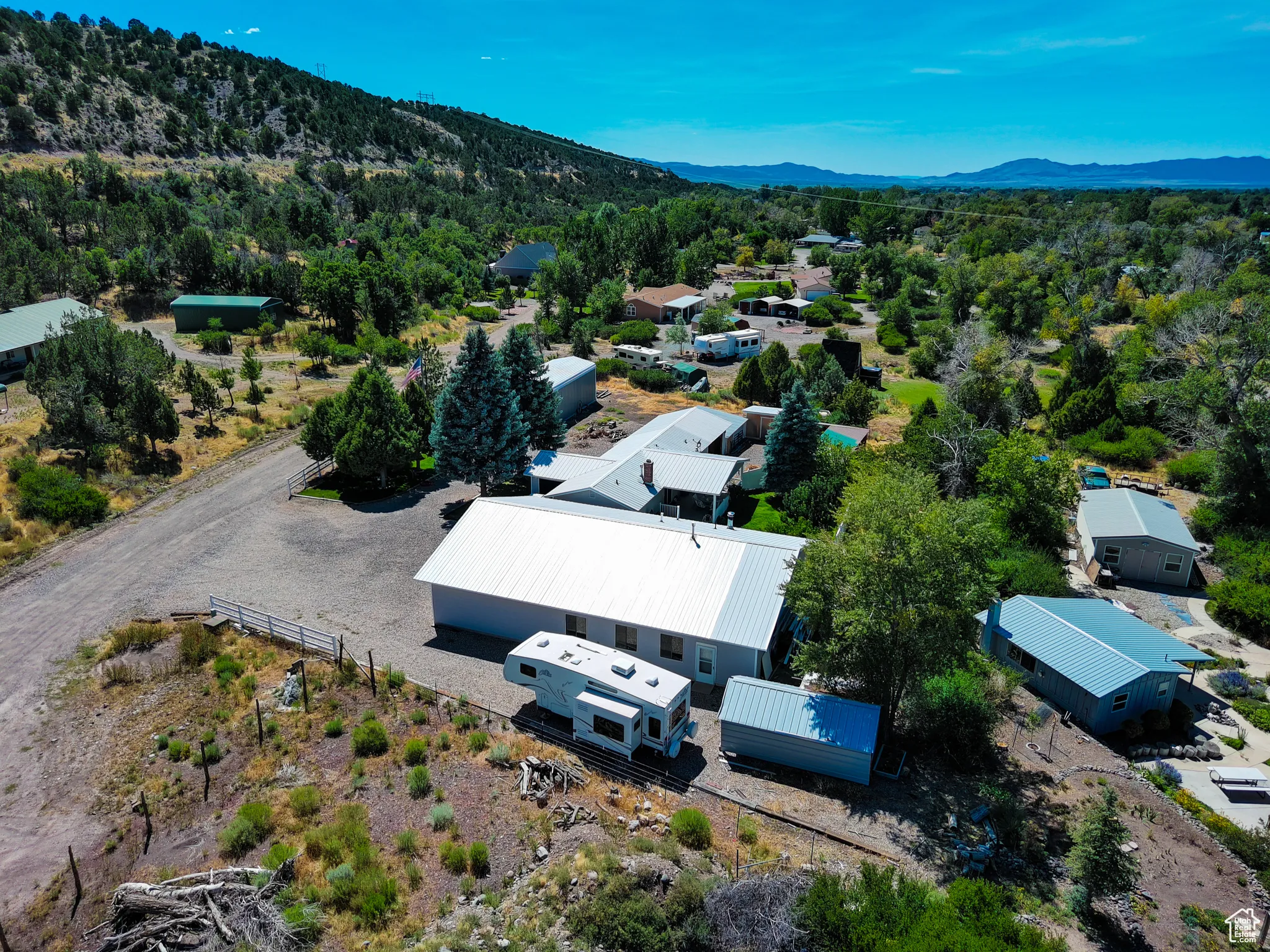 Aerial view of property and surrounding area featuring a forest and a mountainous background