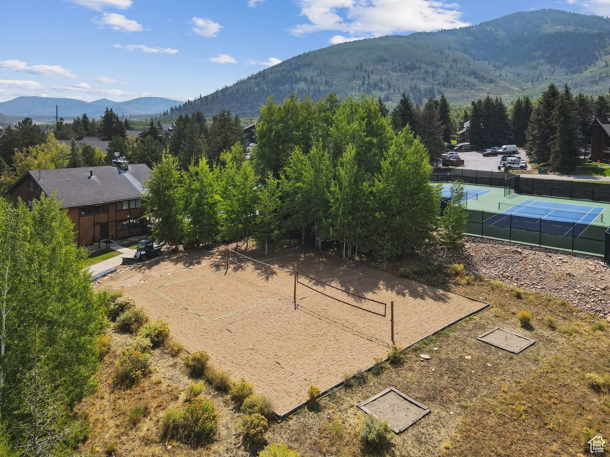 Surrounding community featuring a mountain view, a sunroom, volleyball court, and a patio