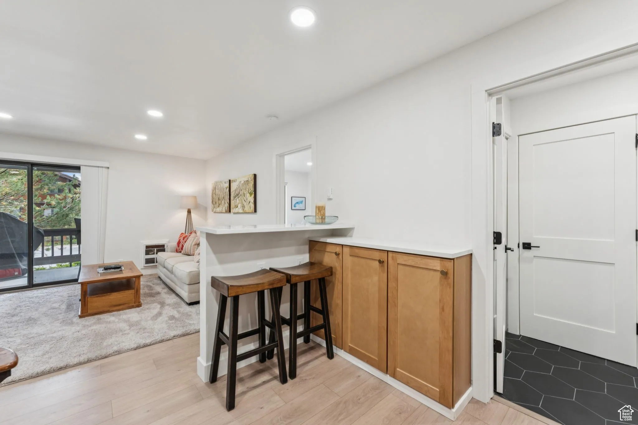 Bar with light countertops, brown cabinets, recessed lighting, and light wood-style flooring
