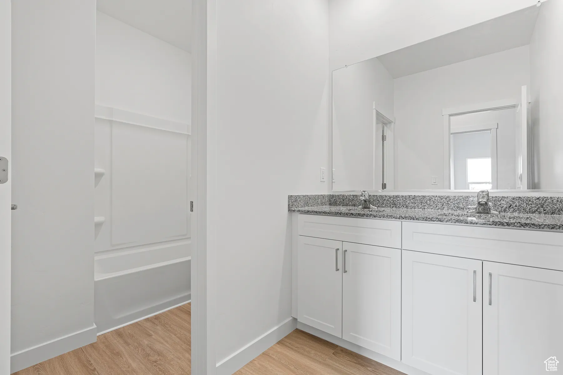 Bathroom with double vanity, light wood-type flooring, and  shower combination