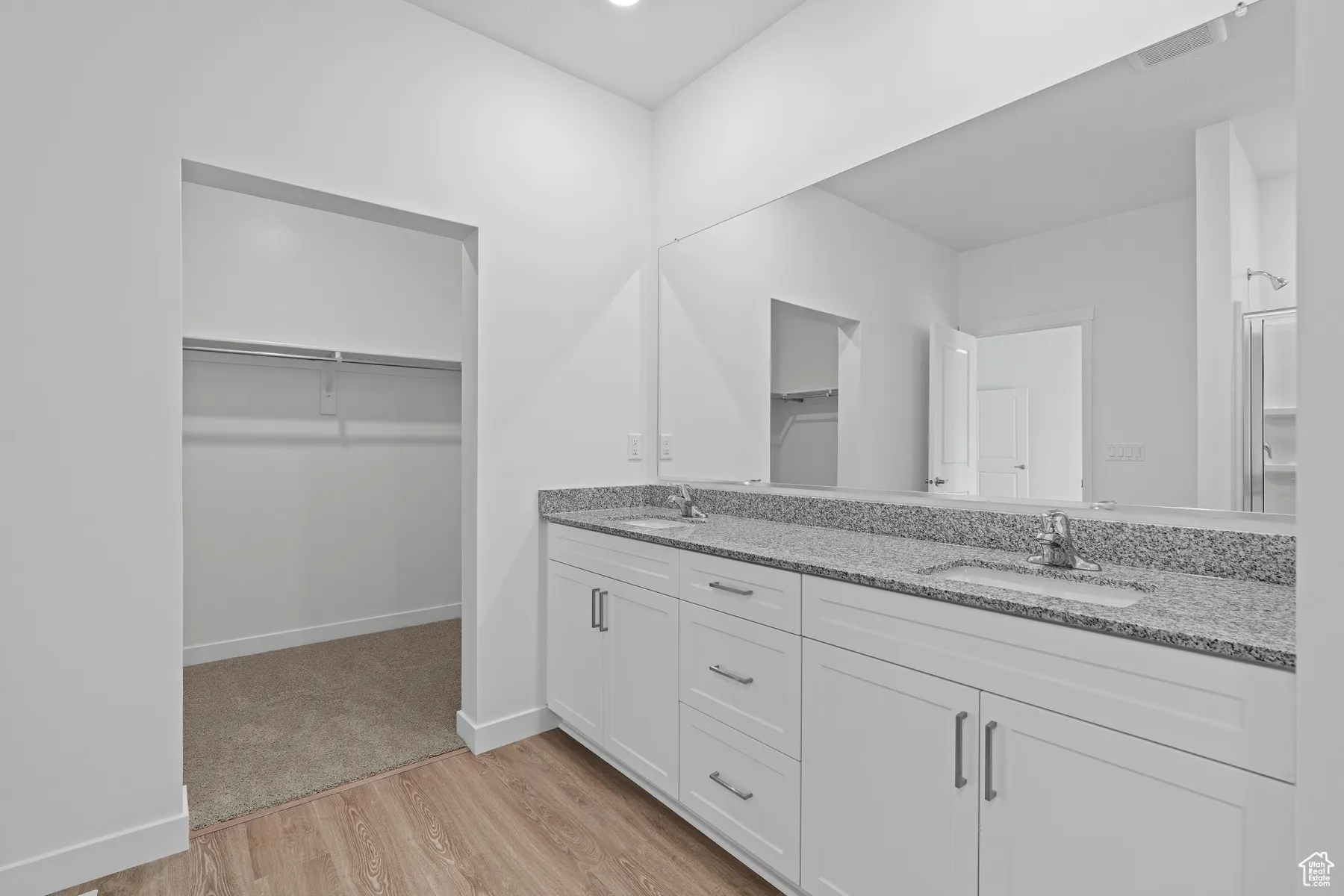 Bathroom with light wood-type flooring, double vanity, and a spacious closet