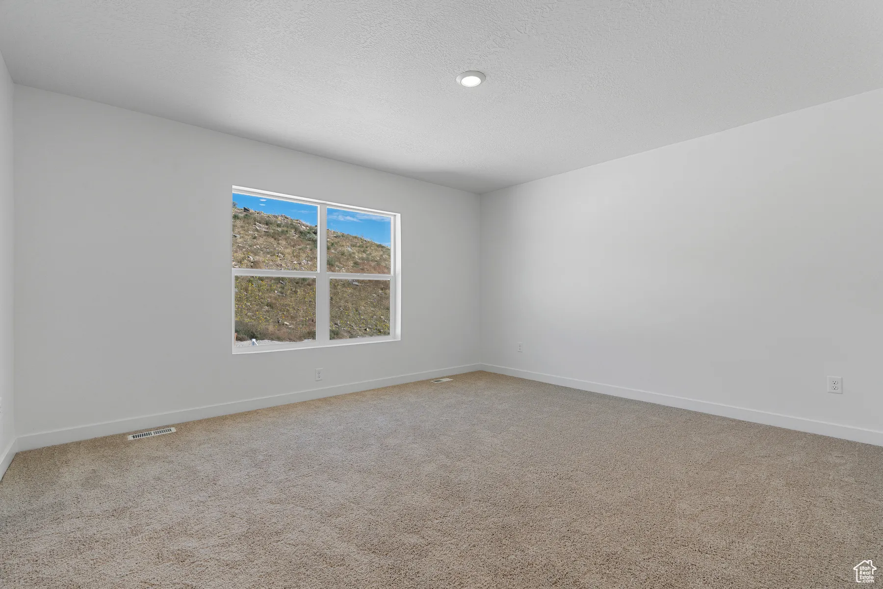 Spare room with light carpet and a textured ceiling
