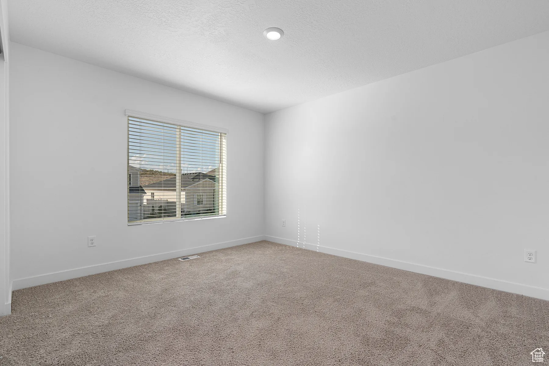 Carpeted spare room featuring a textured ceiling and baseboards