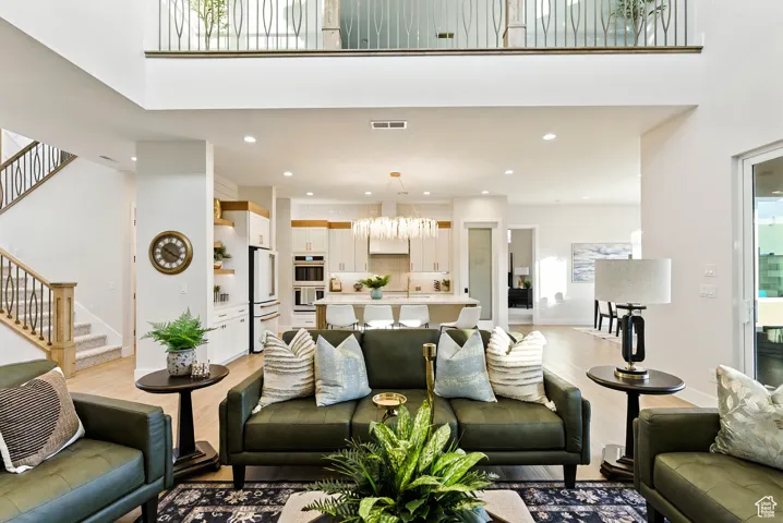 Living room featuring stairway, recessed lighting, light wood finished floors, and a towering ceiling