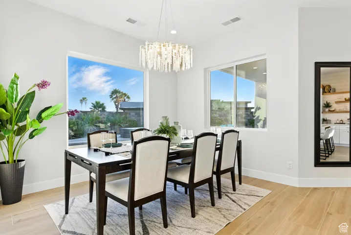 Dining area with light wood finished floors, a chandelier, and recessed lighting