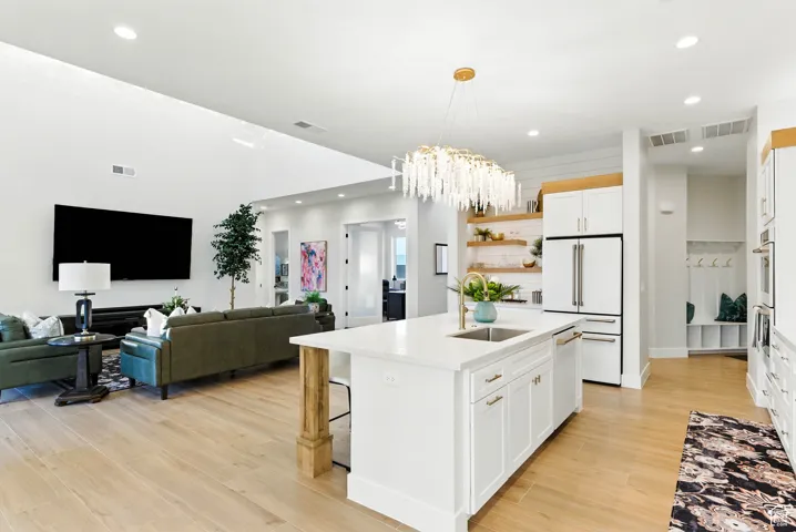Kitchen featuring recessed lighting, white appliances, light countertops, light wood finished floors, and a chandelier