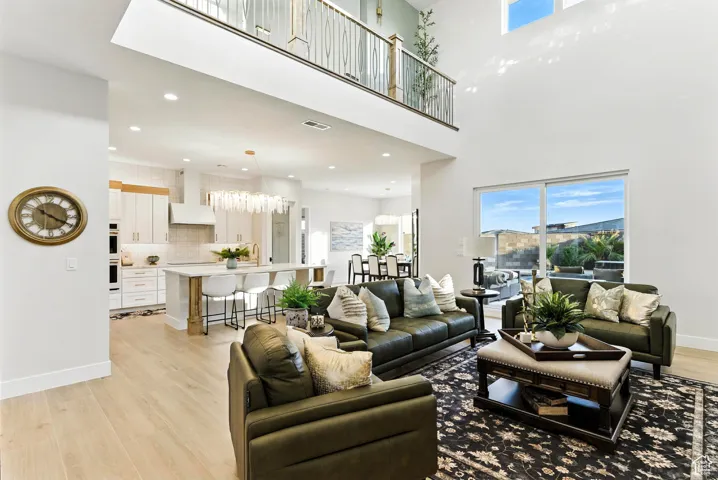 Living area with healthy amount of natural light, light wood-type flooring, recessed lighting, and a towering ceiling