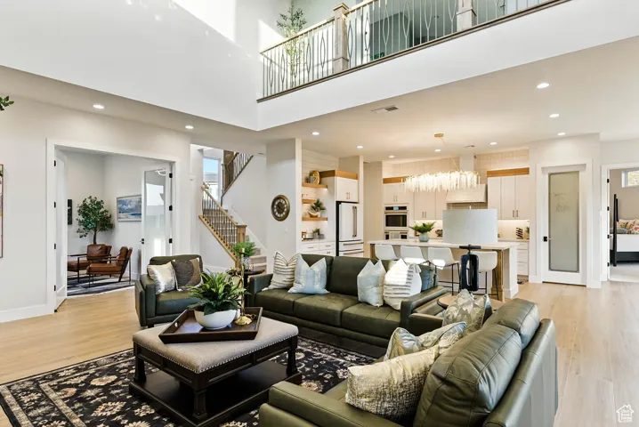 Living room with recessed lighting, light wood-style floors, and a high ceiling