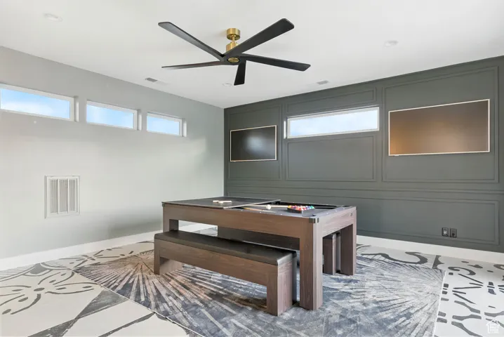 Playroom with plenty of natural light, a ceiling fan, a decorative wall, and tile patterned flooring leading to the large wrap around deck.