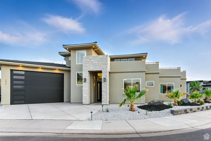Contemporary house featuring stucco siding, stone siding, an attached 3 car garage, and concrete driveway and easy-care land scaping.