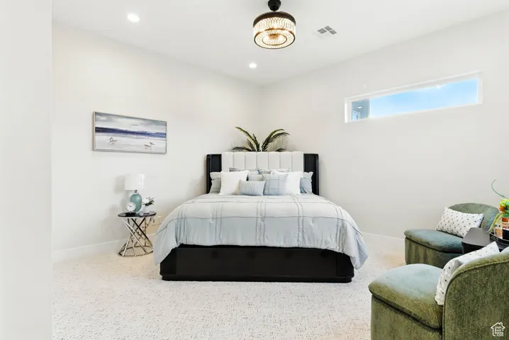 Large, carpeted bedroom with baseboards and recessed lighting.